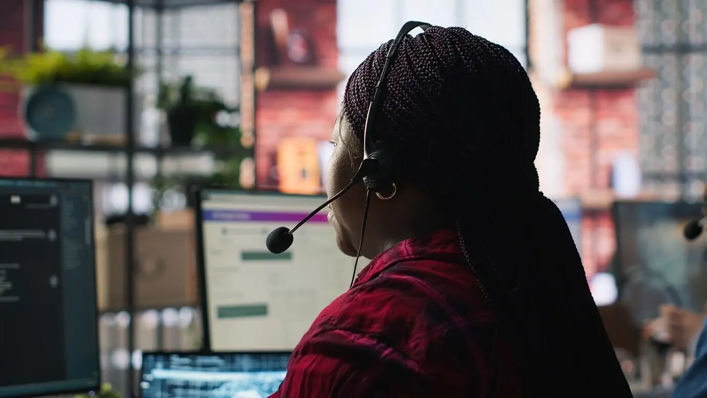 Сотрудник колл-центра в офисе использует ИИ-чатбот для ответов клиентам.